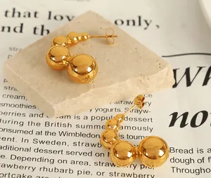 Detailed macro view of gold-plated spherical C-shaped stainless steel hoop earrings
