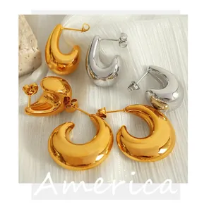 Macro detail showing high-polished irregular C-shaped hoop earrings in gold and silver tones.