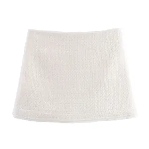 Gros plan sur une mini-jupe en tweed texturé blanc cassé avec motif de tissage détaillé.
