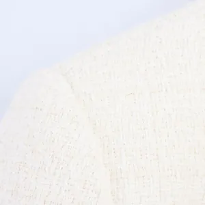 Gros plan sur le tissage complexe du tweed blanc et la couture d'un haut texturé élégant