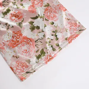 Close-up showing the smooth pink floral satin fabric and precise hemline stitching detail.