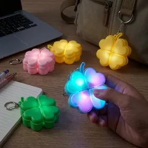 Macro view of multi-color glowing four-leaf clover stress relief keychain held in hand
