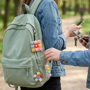 Gros plan de porte-clés pattes de chat fixés à un sac à dos vert à l'extérieur.