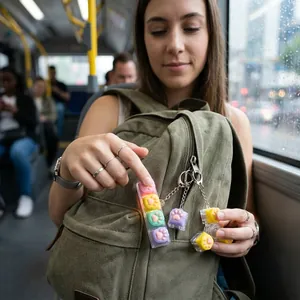 Détail d'un jouet antistress patte de chat coloré accroché à un sac à dos vert