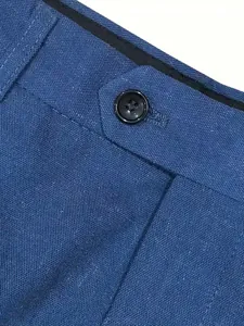 Nahaufnahme des Hosenbunds einer blauen Leinenanzughose mit elegantem schwarzem Knopfdetail