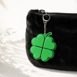 Close-up detail of a green four-leaf clover fidget keychain hanging on a black plush bag
