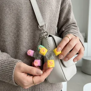Detalle de un llavero fidget spinner con forma de pata de gato macaron colgado de un bolso gris chic