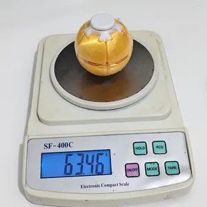 Nahaufnahme eines gelben 3D-gedruckten Planeten-Fidget-Toys mit 63,46g auf einer Waage