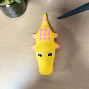 Vista superior de un juguete antiestrés de cocodrilo amarillo con motas rosas decorativas
