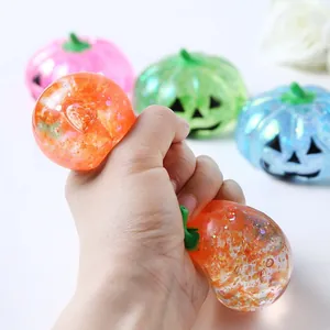 Hand drückt ein funkelndes Halloween-Kürbis-Squishy-Spielzeug zur Stressbewältigung
