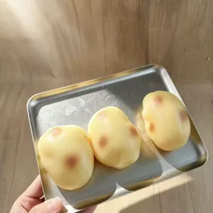 Giocattoli squishy a forma di patate realistiche su un vassoio di metallo.