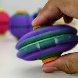 Detail view showing a colorful 3D printed fidget spinning ball held between fingers for play.