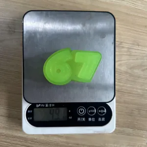 Translucent green glitter number 67 squeeze fidget toy showing weight on a scale