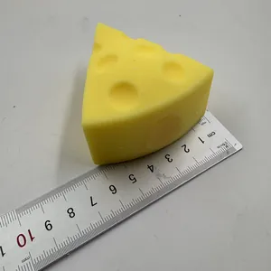 Nahaufnahme eines gelben dreieckigen Käse-Squishy-Stressspielzeugs neben einem Metalllineal