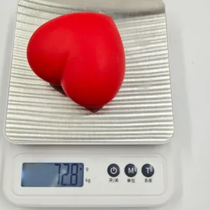 A red heart-shaped squishy stress relief toy weighing 72.8 grams on a digital scale