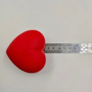 Red heart-shaped squishy slow rebound stress relief toy being measured with a silver ruler