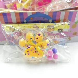 Detail of a cat paw squishy toy with star sequins and colorful pompoms in packaging