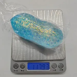 Detailed view of blue glittery peanut squishy toy being weighed on a scale showing 117.93g