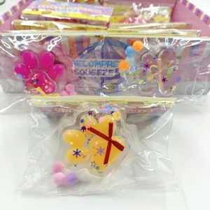 Detailed view of a yellow cat paw squishy toy in its individual packaging with pom-poms