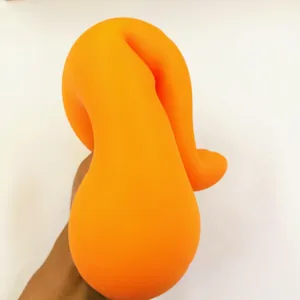 Macro detail of an orange carrot-shaped squishy stress relief toy being squeezed by hand.