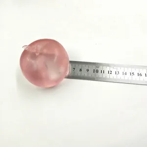 Detailansicht zeigt den Durchmesser eines pinkfarbenen Apfel-Quetschspielzeugs mit Lineal