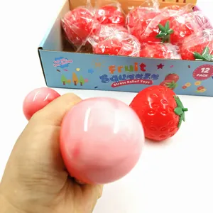Detail of hand squeezing a red strawberry stress relief toy showing soft texture