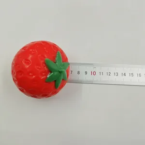 Strawberry squishy toy size measurement with a metal ruler on white background.