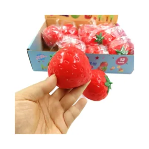 Red strawberry squishy stress relief toy being held by hand with display box