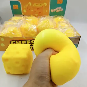 Dettaglio di una mano che schiaccia un giocattolo squishy a cubetti di formaggio giallo relax