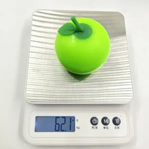 Realistic green apple squishy stress relief toy on a digital scale weighing 62.1 grams