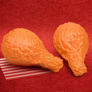Realistic fried chicken leg squishy toys with textured golden finish on red background.
