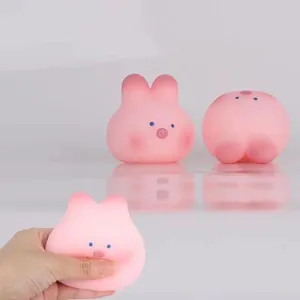 Hand squeezing a soft pink bunny pig stress relief toy with a cute minimalist face