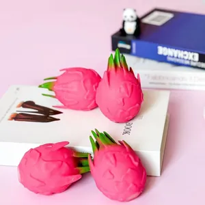 Realistische Drachenfrucht-Quetschspielzeuge zum Stressabbau auf einem rosa Schreibtisch