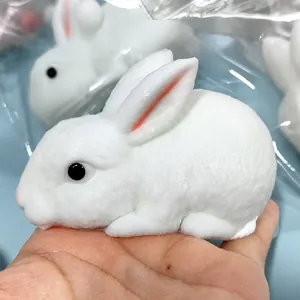 Close-up view of a realistic white rabbit squishy stress relief toy held in a hand