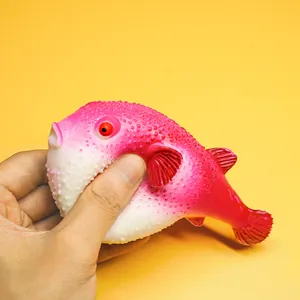 Macro view of hand squeezing a realistic pink pufferfish stress relief toy detail