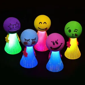 Gros plan de jouets elfes sauteurs lumineux colorés avec visages emoji sur fond noir.