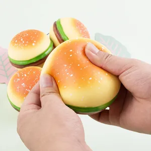 Close-up of hands squeezing a realistic simulation hamburger squishy for stress relief.