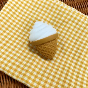 Close-up detail of a soft simulation flour ice cream squishy toy on yellow checkered cloth