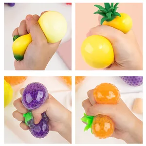 Close-up view of hands squeezing various fruit-shaped water bead stress balls for sensory relief