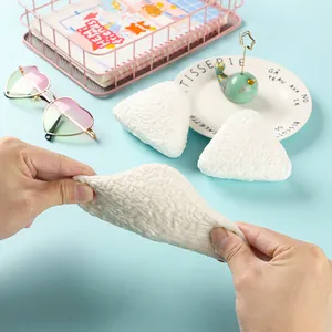 Close-up of a white triangular rice ball squeeze toy being stretched for stress relief