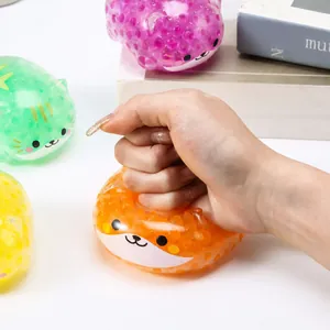Détail d'une main pressant un jouet anti-stress Shiba Inu orange rempli de perles