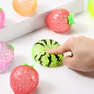 Close-up detail of hand squeezing a squishy fruit stress toy with green watermelon pattern