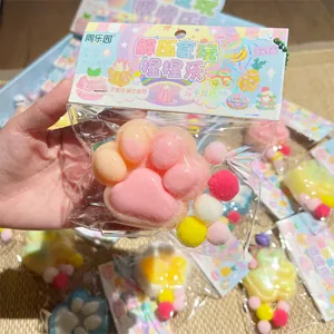 Close-up detail of a pink cat paw squishy toy in clear packaging with colorful poms