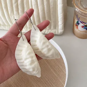 Detailansicht von zwei realistischen weißen Teigtaschen-Squishy-Anhängern in der Hand