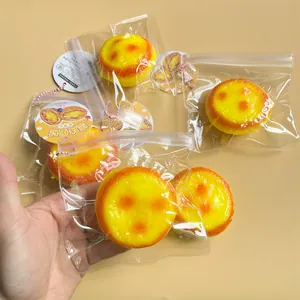 Hand holding several yellow egg tart squishy toys in clear plastic bags for stress relief