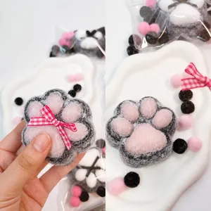 Detail view of a soft plush cat paw squishy toy featuring a pink detachable bowknot