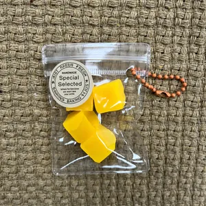 Detailed view of yellow fruit segment squishy cubes inside a clear mini zipper bag with chain