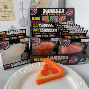 Macro detail view of orange pizza-shaped squeeze toys in boxes and on a white plate