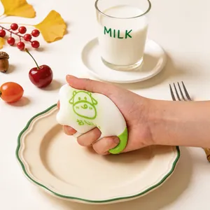 Gros plan d'un jouet anti-stress en silicone en forme de pain de vache pressé par la main.