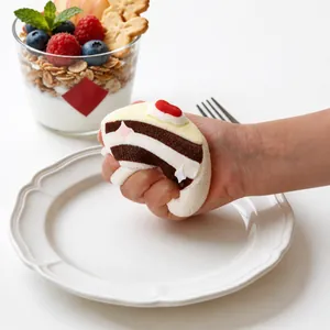 Detailansicht einer Hand, die ein Erdbeerkuchen-Silikon-Squishy-Stressspielzeug drückt